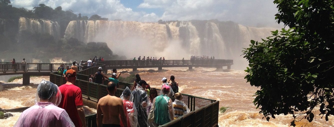 personne en imperméable sur une passerelle d'accès au chutes d'Iguaçu au Brésil.