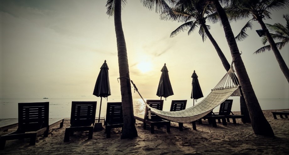 Vue d'une plage typique avec coucher de soleil, hamac, chaises longues et cocotiers au Brésil.