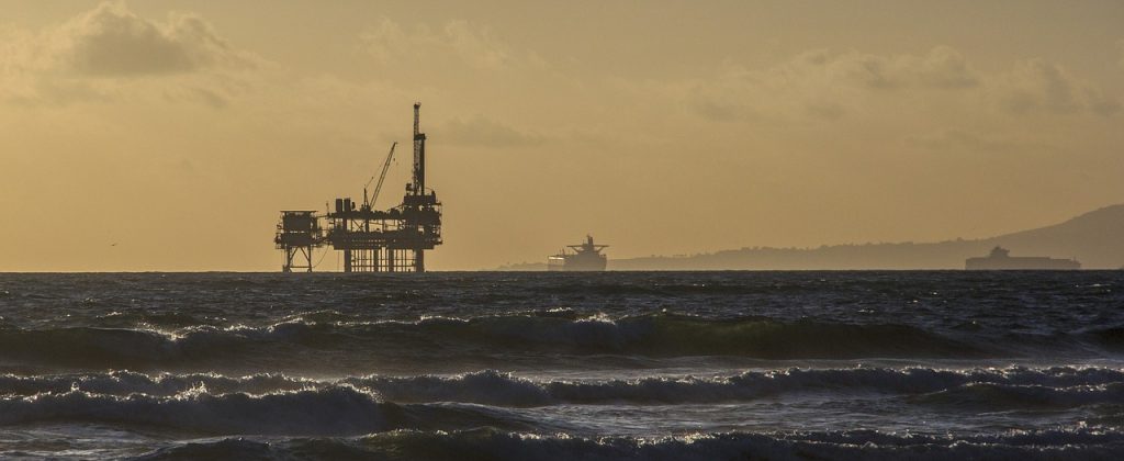 Photo d'une plateforme pétrolière en mer dans le soleil couchant.