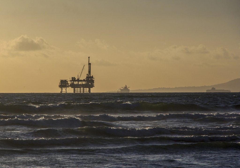 Photo d'une plateforme pétrolière en mer dans le soleil couchant.