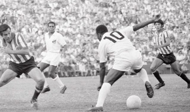 Pelé dribblant lors d'un match, photo en noir et blanc.