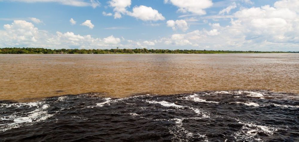 Vue de la rencontres des eaux obscures du Rio Negro avec le Rio Solimões boueux près de Manaus.