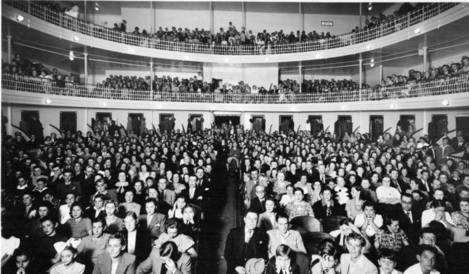 Vue en noir et blanc des spectateurs d'un théätre depuis la scène de celui ci dans les années 50 au Brésil.