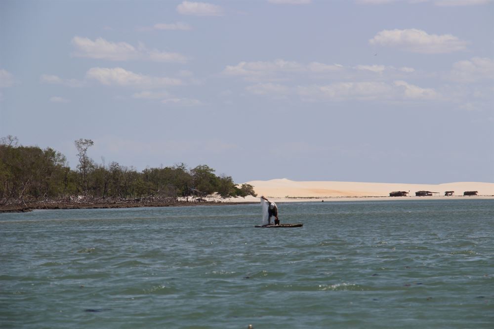 un pécheurs au filet sur la rivière avec des dunes dans le fond.