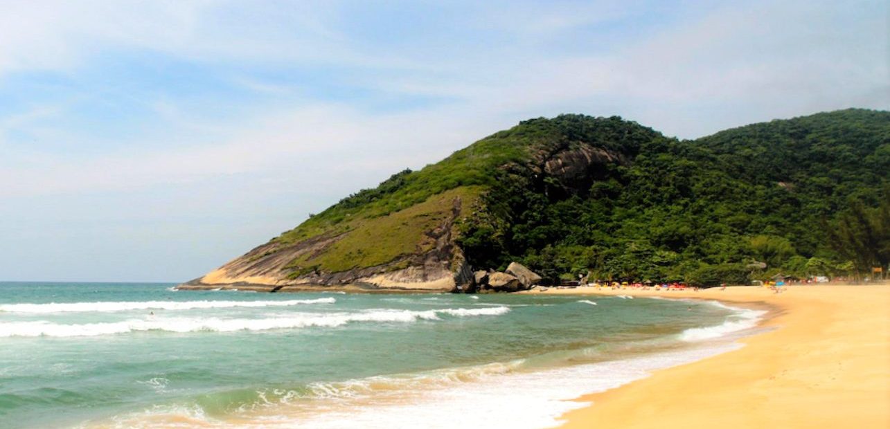 Vue de la belle plage de Grumari à Rio et de la colline couverte de forêt qui la borde.