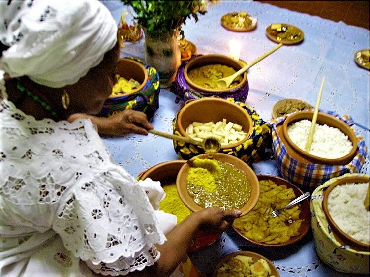 Des recettes traditionnelles bahianaises sont servies par une bahianaise habillée en blanc.