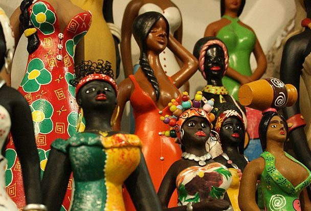 Des statuettes africaines représentent des femmes noires habillées de robes colorées. 